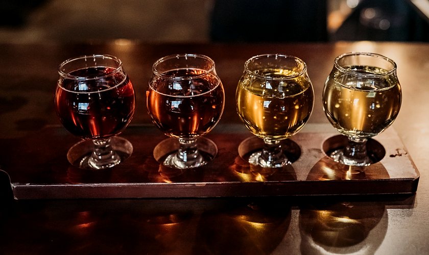 A flight of four ciders on a wooden paddle